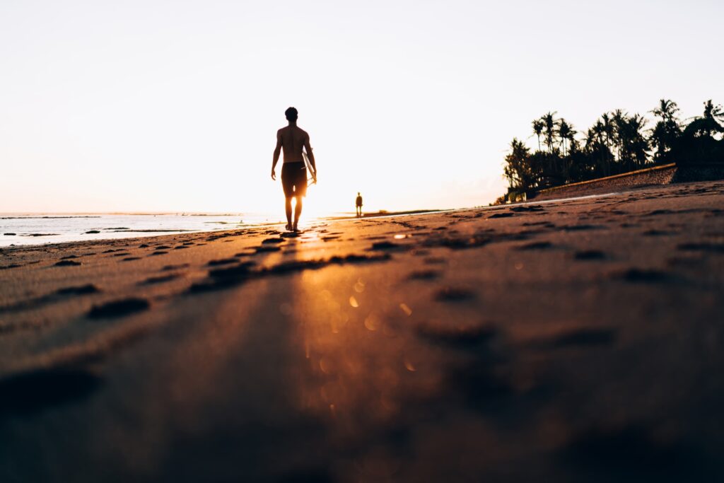 Sportive male surfer walking during summer vacations at Punalu'u Beach in Hawaii